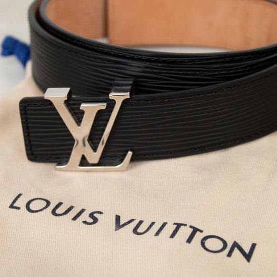 Black Louis Vuitton belt with silver buckle on a beige Louis Vuitton dust bag.