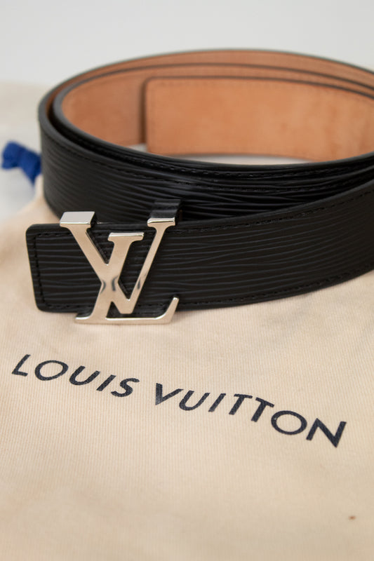 Black Louis Vuitton belt with silver buckle on a beige Louis Vuitton dust bag.