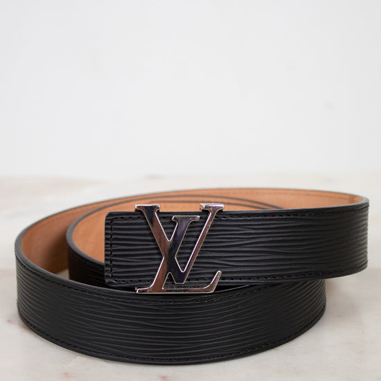 Black and brown belt with a prominent Louis Vuitton logo on a light marble background