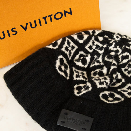 Black beanie with white pattern next to a Louis Vuitton box on a marble surface