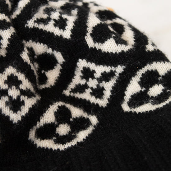 Black knit beanie with white pattern on a white background