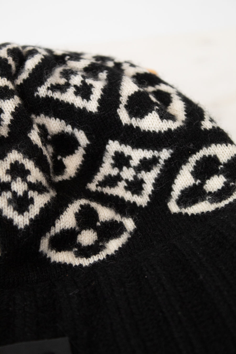 Black knit beanie with white pattern on a white background