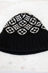 Black knit beanie with white pattern on a marble surface