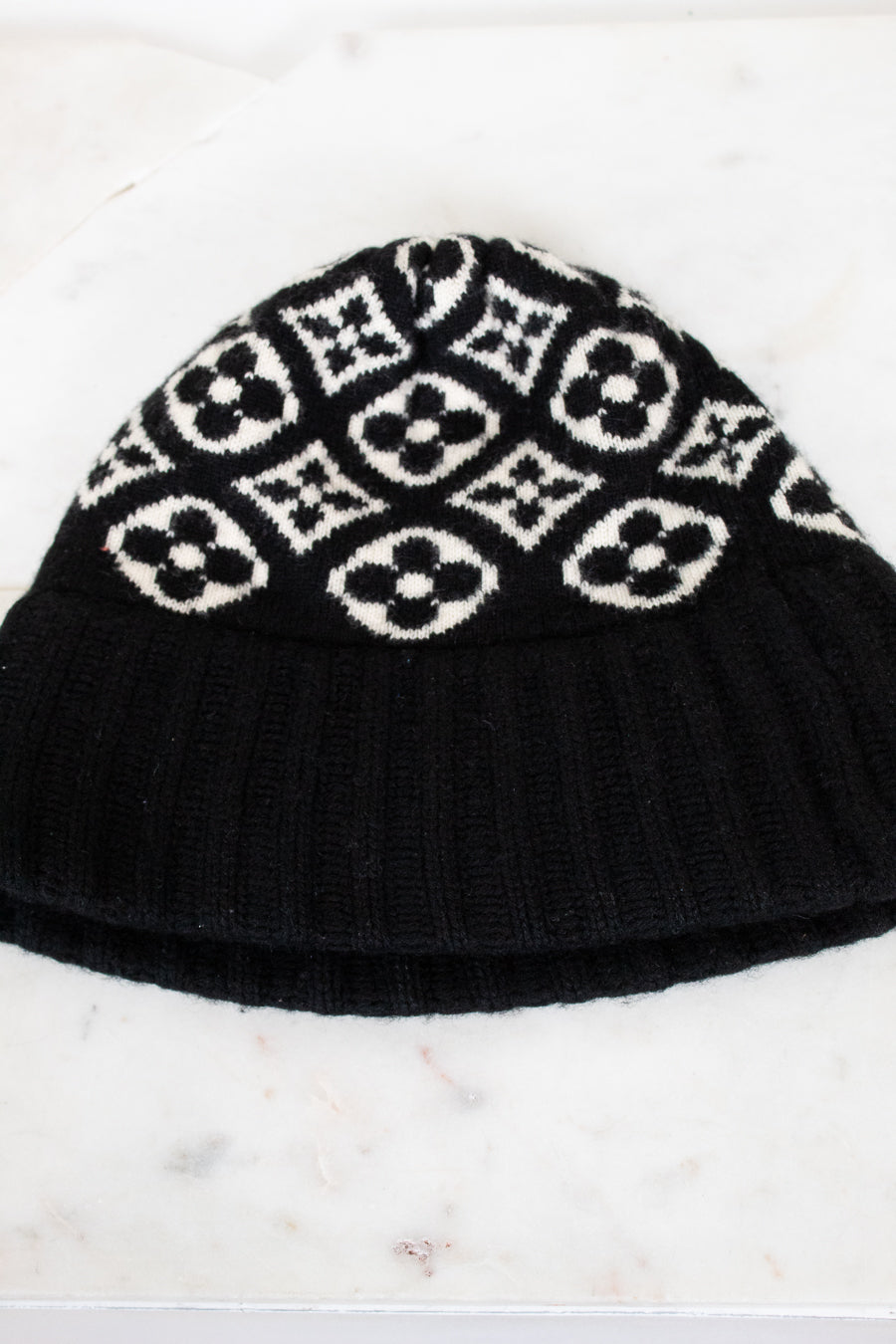 Black knit beanie with white pattern on a marble surface