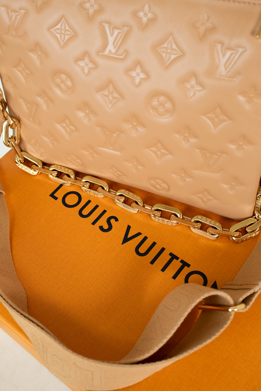 Louis Vuitton beige handbag on orange box with brand logo 