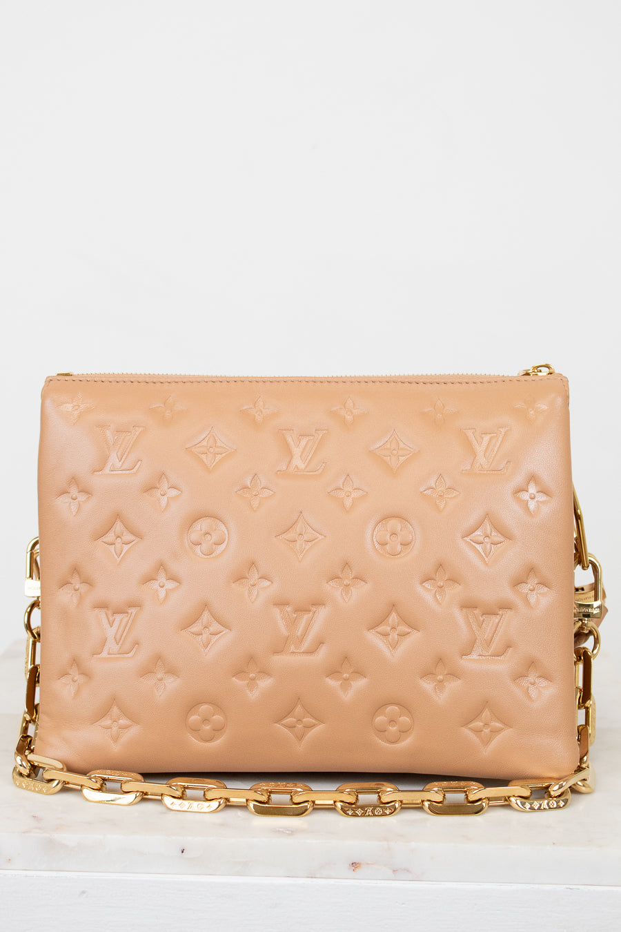 Beige handbag with gold chain strap on a white background