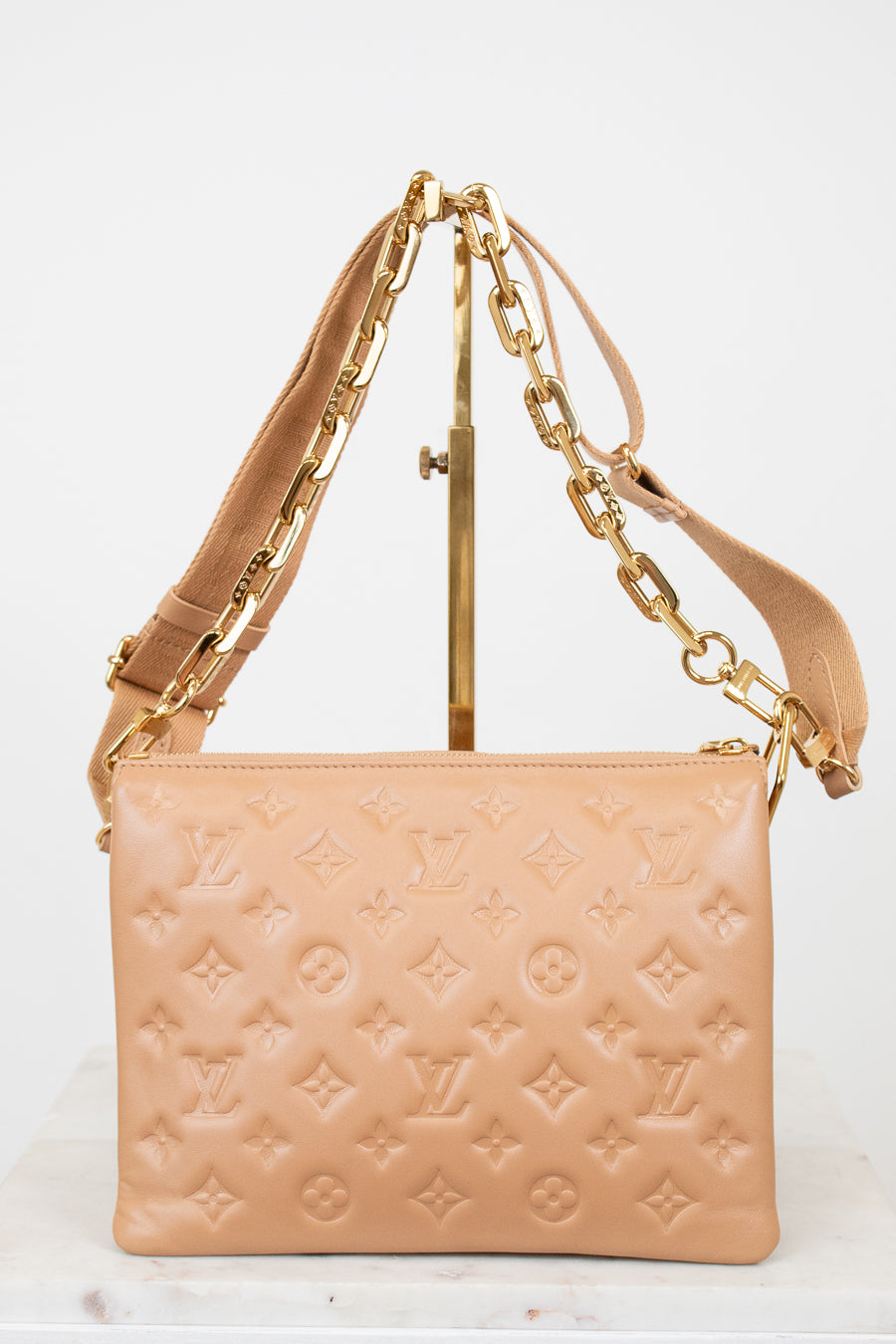 Beige handbag with gold chain strap on a white background