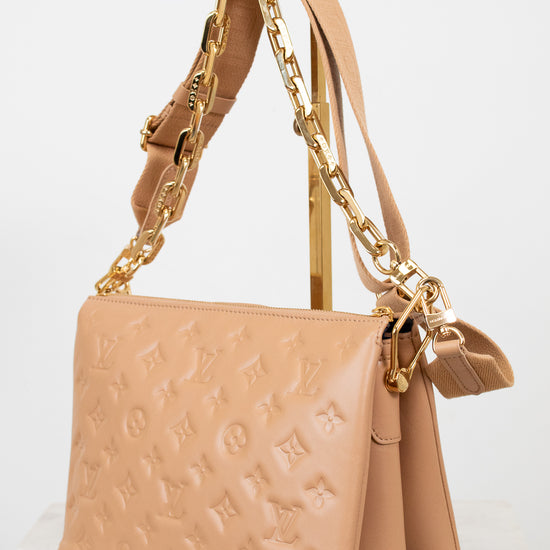 Beige handbag with gold chain strap on a light background
