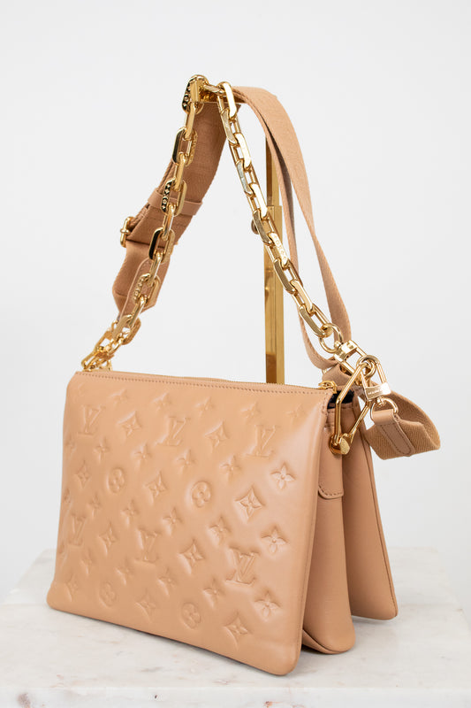 Beige handbag with gold chain strap on a light background