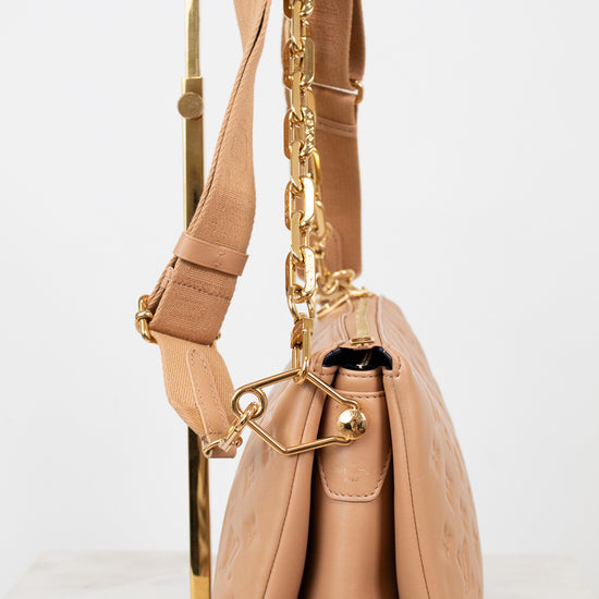 Beige handbag with gold chain detail on a white background