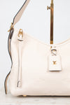 A close-up of a Louis Vuitton shoulder bag in off-white pebbled leather with gold-tone hardware and a matching leather hangtag featuring the LV logo.