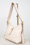 A cream-colored pebbled leather hobo shoulder bag with gold-tone hardware, displayed on a wooden stand against a light gray background.