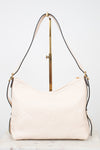 A light cream-colored leather shoulder bag with a subtle embossed monogram pattern, displayed on a gold-colored stand against a white background.