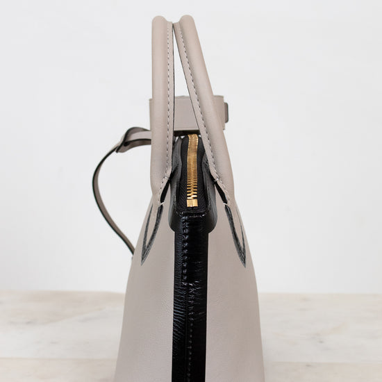 White handbag with black zipper on a light gray background