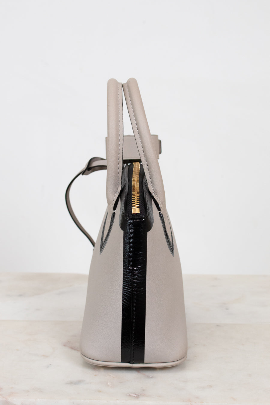 White handbag with black zipper on a light gray background