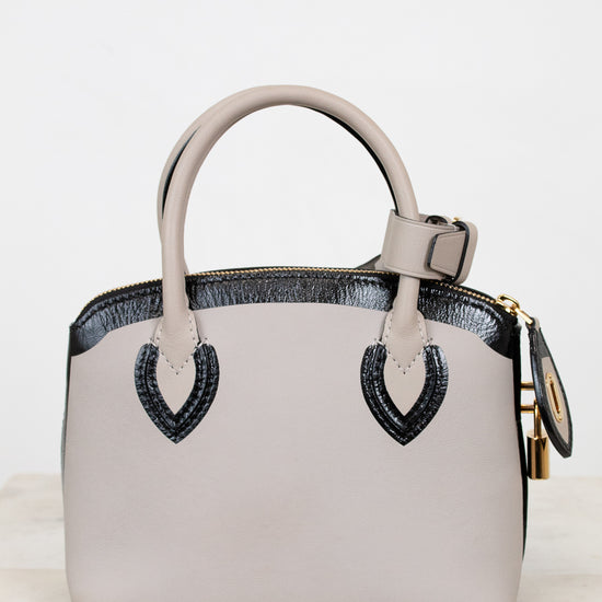 White handbag with black accents on a marble surface