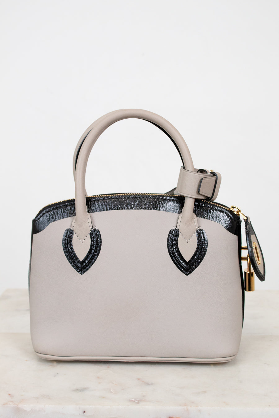 White handbag with black accents on a marble surface