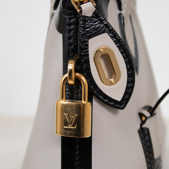 Close-up of a white handbag with a gold padlock on a light gray background