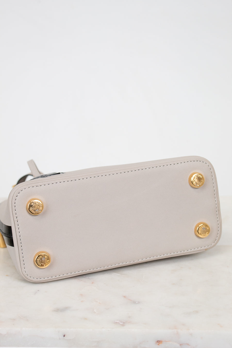 Light gray wallet with gold accents on a marble surface