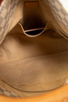 Close-up view of the interior of a handbag, showing a beige fabric lining, a top pocket, and part of the patterned exterior near the opening.
