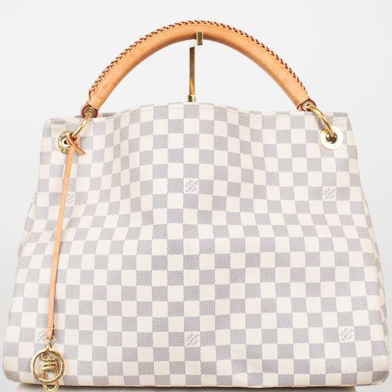 A Louis Vuitton handbag in Damier Azur coated canvas, featuring a light gray and white checkered pattern, a tan leather top handle, and gold-tone hardware.