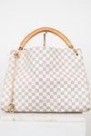 A Louis Vuitton handbag in Damier Azur coated canvas, featuring a light gray and white checkered pattern, a tan leather top handle, and gold-tone hardware.