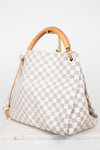 A Louis Vuitton Damier Azur canvas handbag with a light gray and white checkered pattern, tan leather top handles, and gold-tone hardware, displayed on a white marble surface against a white background.