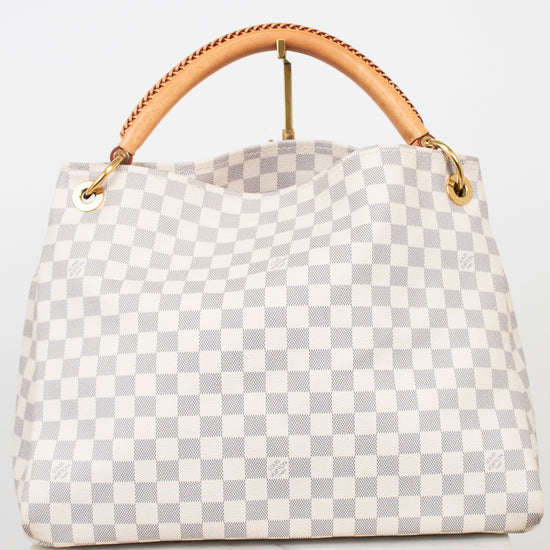 A light gray and white checkered handbag with a tan leather top handle and gold-tone hardware, displayed on a white surface against a white background.