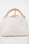 A light gray and white checkered handbag with a tan leather top handle and gold-tone hardware, displayed on a white surface against a white background.