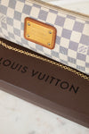 A close-up of a Louis Vuitton monogram bag featuring the Damier Azur check pattern, a gold-tone metal logo plate, and a gold chain strap, resting on a brown Louis Vuitton box.