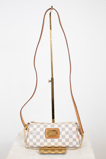 A Louis Vuitton shoulder bag in Damier Azur canvas with a brown leather strap and gold-tone hardware, displayed on a stand against a white background.