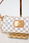 A Louis Vuitton shoulder bag in Damier Azur canvas with a blue and white checkered pattern, tan leather trim, and a gold-tone metal plaque and on a light marble background.