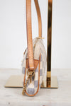 A close-up side view of a Louis Vuitton shoulder bag in Damier Ebene canvas with tan leather trim, resting on a gold-colored display stand.