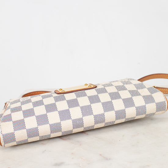 A Louis Vuitton shoulder bag in the Damier Azur canvas, featuring a cream and light blue checkered pattern with tan leather trim and a gold-tone turn-lock clasp, showing the bottom on a white marble surface.