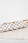 A Louis Vuitton shoulder bag in the Damier Azur canvas, featuring a cream and light blue checkered pattern with tan leather trim and a gold-tone turn-lock clasp, showing the bottom on a white marble surface.