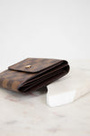 Brown wallet with gold accents on a white marble surface