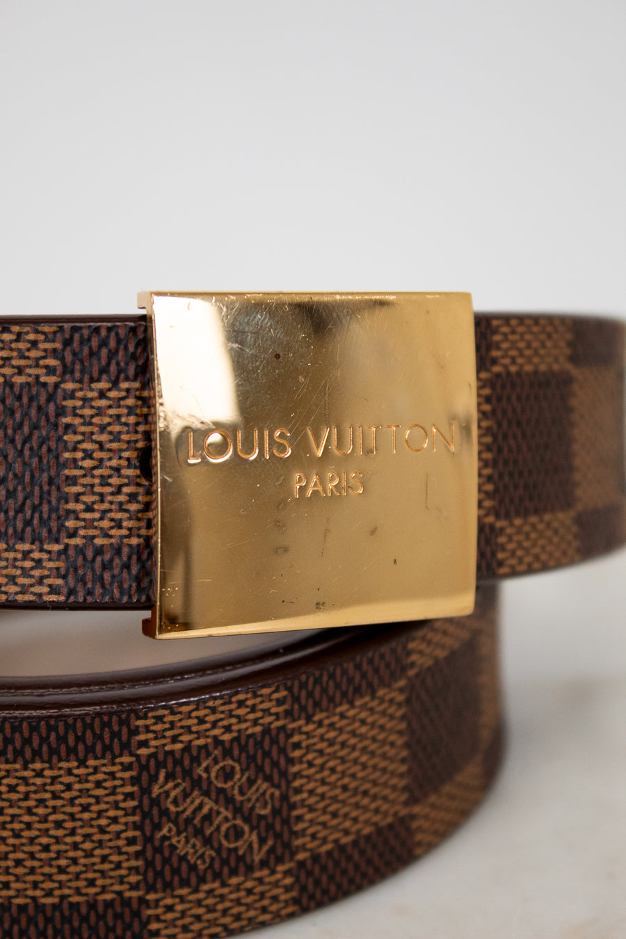 Louis Vuitton belt with gold buckle on a light gray background