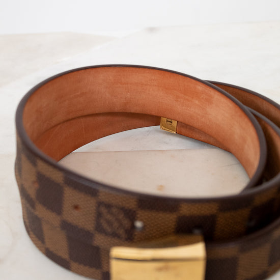 Brown checkered belt with gold buckle on a light background