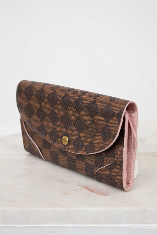 Brown checkered wallet with pink interior on a white surface