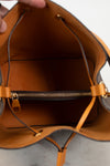 Close-up of a brown interior of handbag with gold zipper hardware.