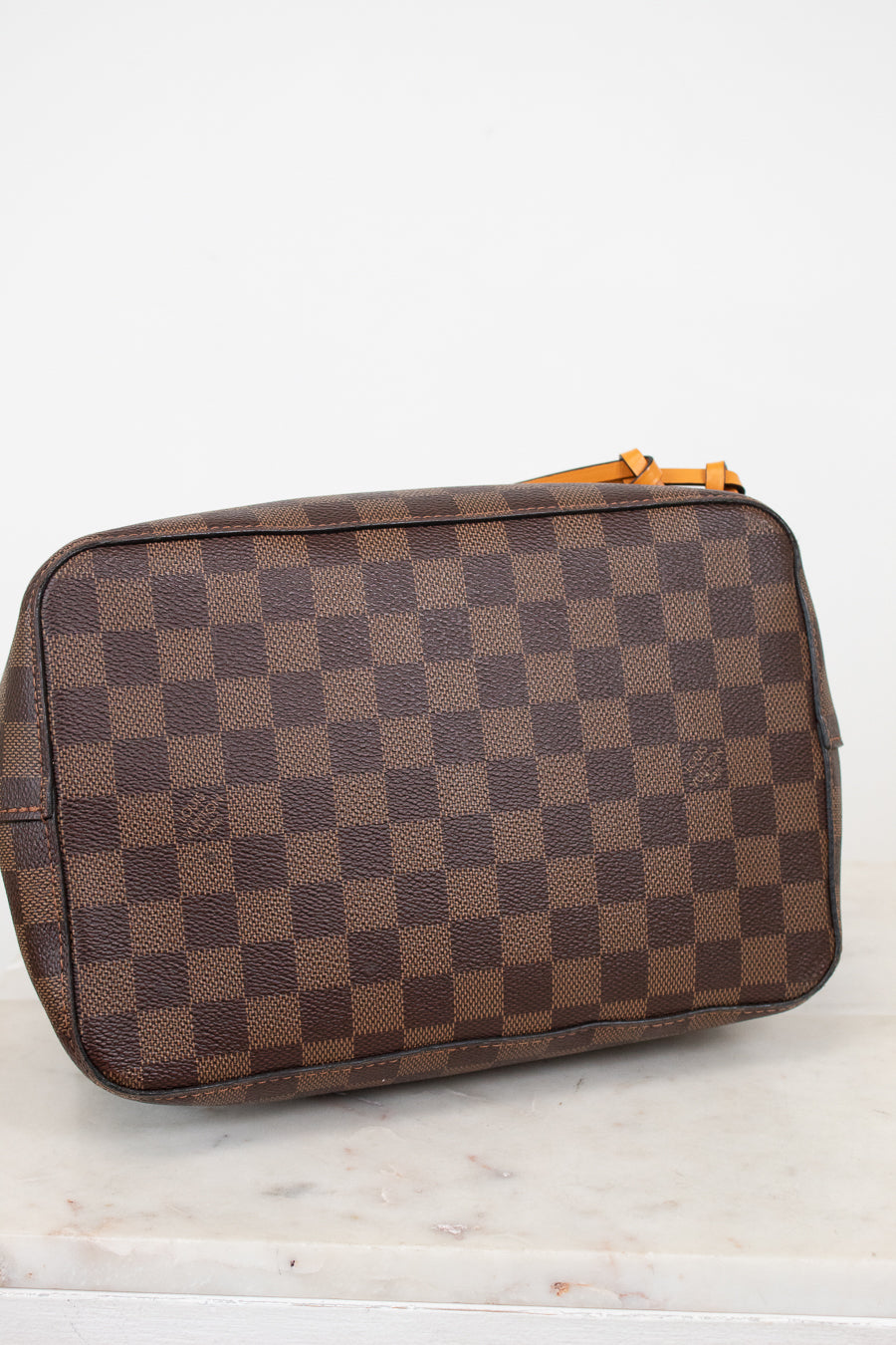 Bottom view of brown checkered tote bag on a white marble surface