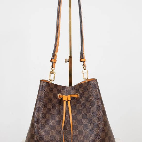 Brown checkered handbag with gold and orange accents on a white background