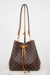 Brown checkered handbag with gold and orange accents on a white background