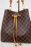 Brown checkered handbag with orange leather straps on a white background