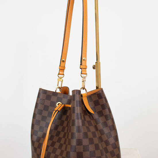 Brown checkered handbag with orange straps on a white background