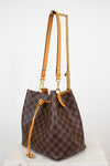 Brown checkered handbag with orange straps on a white background
