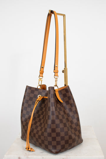 Brown checkered handbag with orange straps on a white background