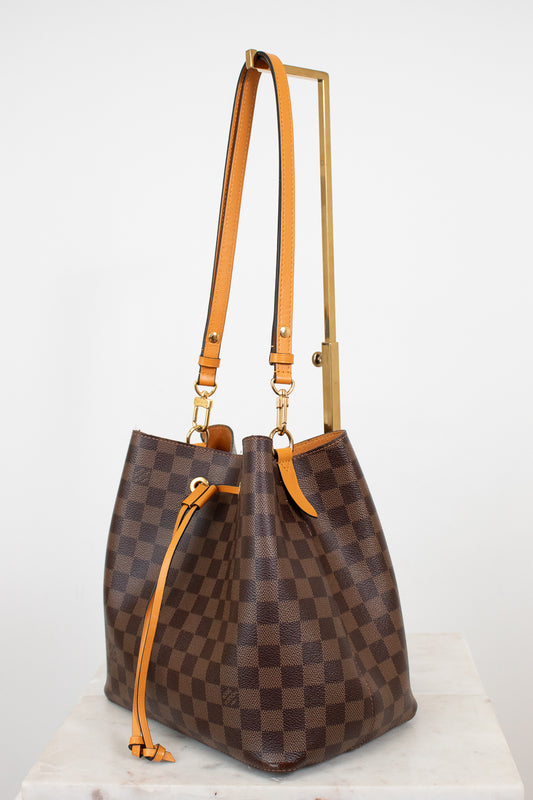 Brown checkered handbag with orange straps on a white background