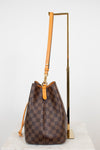 Brown checkered handbag with orange leather strap on a white background