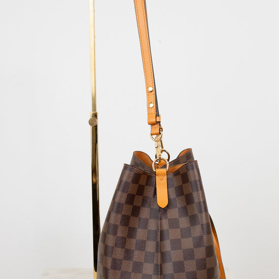 Brown checkered handbag with orange handle on a white background